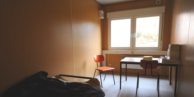 ein sehr kleines Zimmer mit einem schmalen Bett und einem kleinen Tisch ein sehr kleines Zimmer mit einem schmalen Bett und einem kleinen Tisch