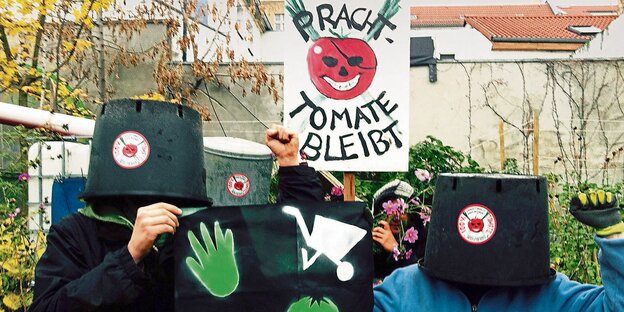 Menschen mit Pflanzenkübeln über dem Kopf und einem Plakat auf welchem steht: "Prachttomate bleibt" Menschen mit Pflanzenkübeln über dem Kopf und einem Plakat auf welchem steht: "Prachttomate bleibt"