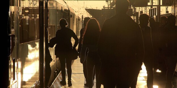 Fahrgäste auf einem Bahnsteig - im Gegenlicht der Abendsonne Fahrgäste auf einem Bahnsteig - im Gegenlicht der Abendsonne