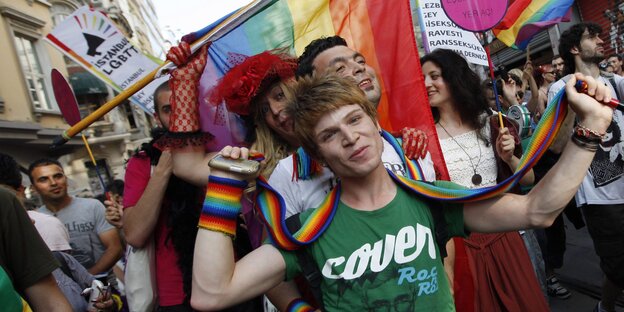 Menschen tragen regenbogenfarbene Tücher und feiern