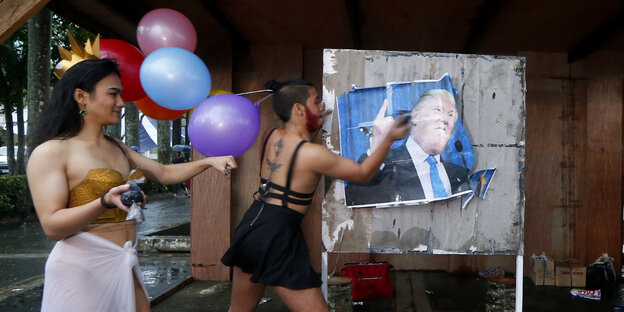 Zwei Mitglieder der LGBT-Community verschmutzen aus Protest ein Plakat von Donald Trump. Zwei Mitglieder der LGBT-Community verschmutzen aus Protest ein Plakat von Donald Trump.