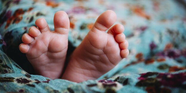 Ein paar Babyfüße auf einer blaugemusterten Decke Ein paar Babyfüße auf einer blaugemusterten Decke