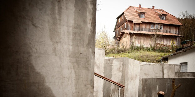 Betonstelen im Vordergrund, dahinter ein rustikales Holzhaus Betonstelen im Vordergrund, dahinter ein rustikales Holzhaus