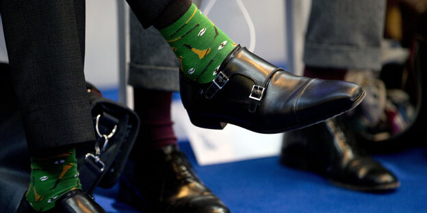 Jemand trägt grüne Socken und hat die Beine übereinander geschlagen