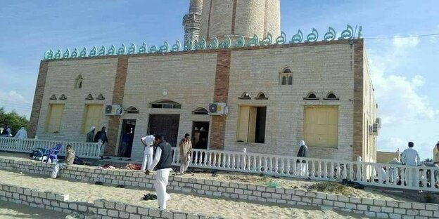 Menschen stehen vor einer Moschee Menschen stehen vor einer Moschee