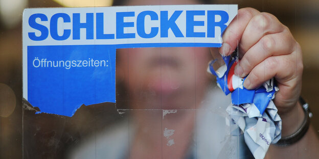 Eine Frau entfernt das Firmenlogo der Drogeriekette Schlecker Eine Frau entfernt das Firmenlogo der Drogeriekette Schlecker