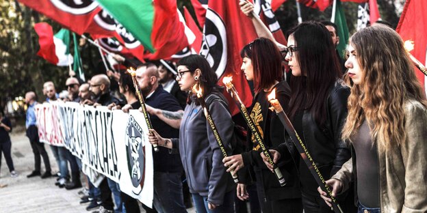 Demoteilnehmer mit Transparent. Im Vordergrund: mehrere Demonstrantinnen mit Fackeln in der Hand Demoteilnehmer mit Transparent. Im Vordergrund: mehrere Demonstrantinnen mit Fackeln in der Hand