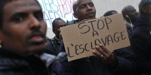 Zwei Männer halten ein Schild mit der Aufschrift "Stop a l'esclavage" Zwei Männer halten ein Schild mit der Aufschrift "Stop a l'esclavage"
