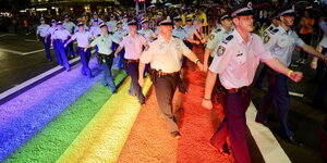 Polizisten laufen über einen Zebrastrafen aus Regenbogenfarben