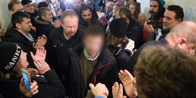 Fabio geht durch eine Menschenmenge, sein Gesicht ist verpixelt