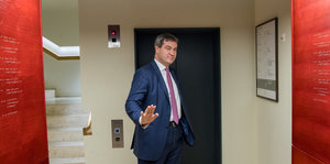 Markus Söder steht vor einem Aufzug