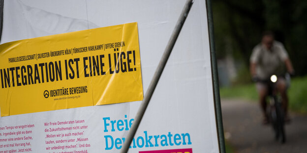 ein gelber Aufkleber der Identitären, der auf einem FDP-Wahlplakat klebt. Darauf steht „Integration ist eine Lüge“ ein gelber Aufkleber der Identitären, der auf einem FDP-Wahlplakat klebt. Darauf steht „Integration ist eine Lüge“