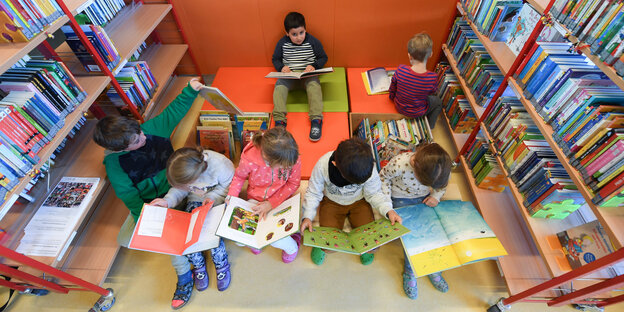 Schüler mit Büchern zwischen Bücherregalen Schüler mit Büchern zwischen Bücherregalen