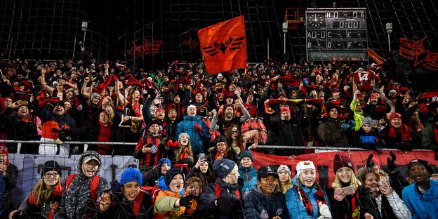Viele Menschen tragen rote Schals und schwingen rote Fahnen des Östersunds FK Viele Menschen tragen rote Schals und schwingen rote Fahnen des Östersunds FK