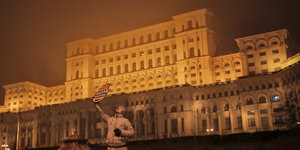 Mensch mit Papphand vor einem großen Gebäude