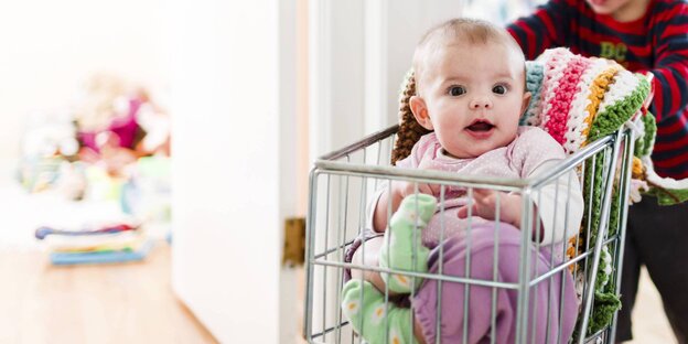 Kleines Kind schiebt Baby in einem Wagen Kleines Kind schiebt Baby in einem Wagen