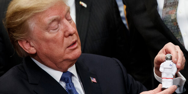 Donald Trump hält die Plastikfigur eines Astronauten Donald Trump hält die Plastikfigur eines Astronauten