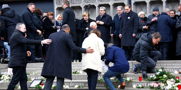 trauernde Menschen stehen vor einer Kirche, einige legen Kränze nieder trauernde Menschen stehen vor einer Kirche, einige legen Kränze nieder