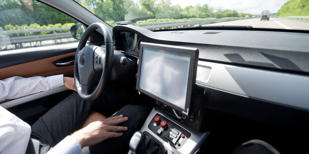 Die Hände eines Autofahrers liegen in seinem Schoß statt auf dem Lenkrad Die Hände eines Autofahrers liegen in seinem Schoß statt auf dem Lenkrad