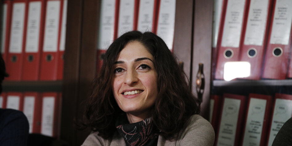 Meşale Tolu sitzt lächelnd vor einem Bücherregal