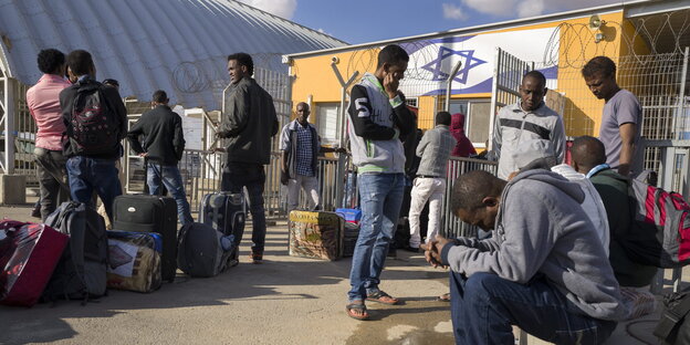 Flüchtlinge vor einer israelischen Fahne an einer Grenzanlage Flüchtlinge vor einer israelischen Fahne an einer Grenzanlage