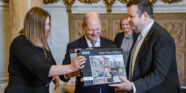 CDU-Politiker André Trepoll (rechts) überreicht Hamburgs Bürgermeister Olaf Scholz und der zweiten Bürgermeisterin Katharina Fegebank ein Puzzle, das die Rote Flora zeigt. CDU-Politiker André Trepoll (rechts) überreicht Hamburgs Bürgermeister Olaf Scholz und der zweiten Bürgermeisterin Katharina Fegebank ein Puzzle, das die Rote Flora zeigt.
