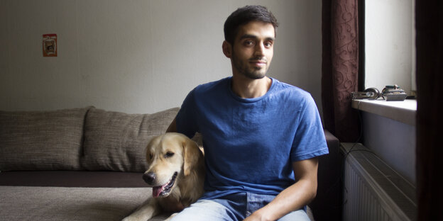 Ein Mann sitzt mit einem Hund auf seiner Couch Ein Mann sitzt mit einem Hund auf seiner Couch