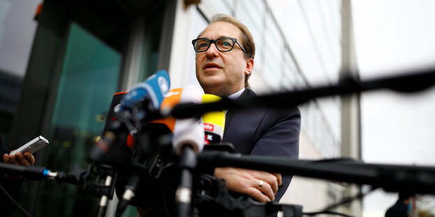 Dobrindt steht vor mehreren Mikrofonen Dobrindt steht vor mehreren Mikrofonen