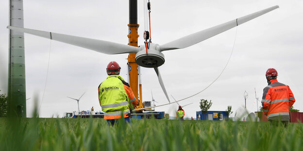 Ein Kran hebt einen Rotor auf ein Windrad Ein Kran hebt einen Rotor auf ein Windrad