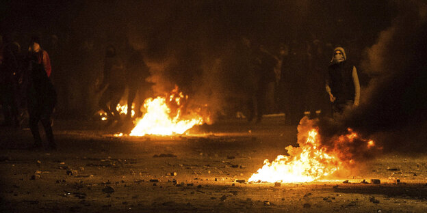 Vermummte Protestler neben offenen Feuerstellen auf der Straße Vermummte Protestler neben offenen Feuerstellen auf der Straße