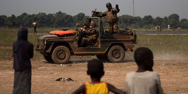 Ein französischer Soldat auf einem Jeep winkt Kindern zu Ein französischer Soldat auf einem Jeep winkt Kindern zu