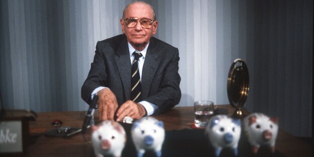 Vier Sparschweine stehen vor einem alten Mann im Anzug. Es ist der Moderator Robert Lemke. Vier Sparschweine stehen vor einem alten Mann im Anzug. Es ist der Moderator Robert Lemke.