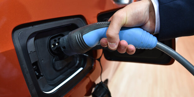 Ladestecker wird an E-Auto gehalten Ladestecker wird an E-Auto gehalten