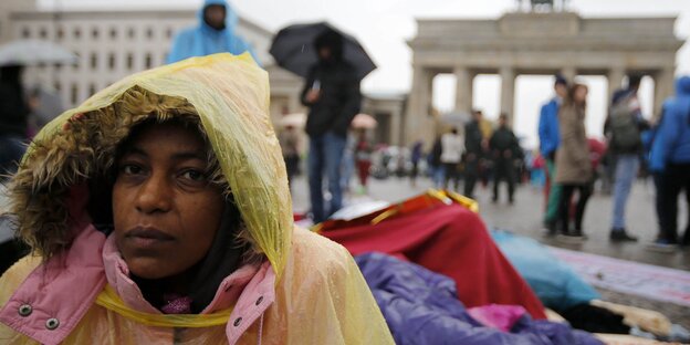 Eine Frau im Anorak sitzt auf dem Pariser Platz vor dem Brandenburger Tor in Berlin Eine Frau im Anorak sitzt auf dem Pariser Platz vor dem Brandenburger Tor in Berlin