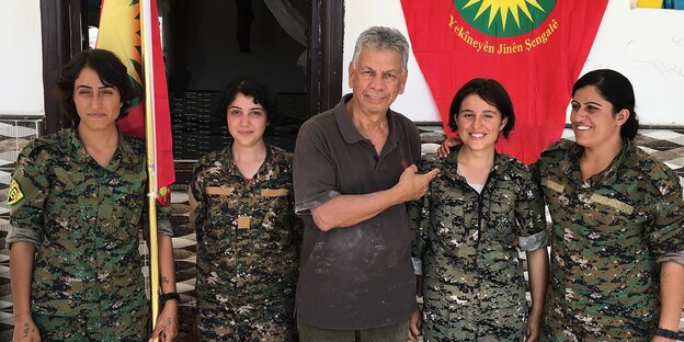 Ein Mann in zivil steht zwischen vier Frauen in Militäruniformen. Ein Mann in zivil steht zwischen vier Frauen in Militäruniformen.