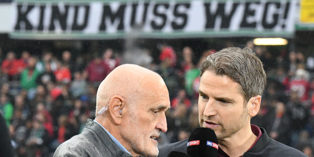 Hannover-96-Präsident Martin Kind gibt in der HDI-Arena ein Interview, im HIntergrund ist ein Banner mit dem Text "Kind muss weg" zu sehen. Hannover-96-Präsident Martin Kind gibt in der HDI-Arena ein Interview, im HIntergrund ist ein Banner mit dem Text "Kind muss weg" zu sehen.