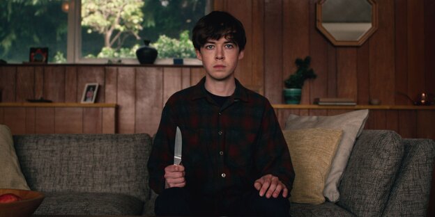 Ein junge sitzt mit einem Messer in der Hand auf einem Sofa. Ein junge sitzt mit einem Messer in der Hand auf einem Sofa.