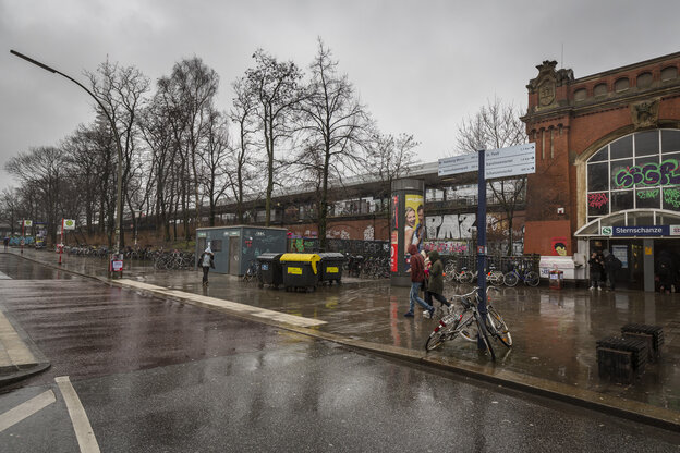 S-Bahn-Gleise auf einer Trasse führen in ein rotes Backsteingebäude. Davor ein breiter Gehsteig und eine Straße. S-Bahn-Gleise auf einer Trasse führen in ein rotes Backsteingebäude. Davor ein breiter Gehsteig und eine Straße.