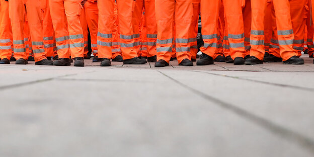 Die Beine vieler Mitarbeiter der Stadtreinigung stehen nebeneinander Die Beine vieler Mitarbeiter der Stadtreinigung stehen nebeneinander