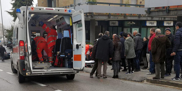 Ein Krankenwagen, in der Nähe stehen einige Menschen Ein Krankenwagen, in der Nähe stehen einige Menschen