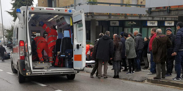 Ein Krankenwagen, in der Nähe stehen einige Menschen