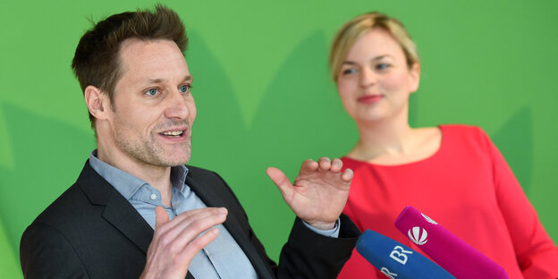 Ein Mann und eine Frau vor einer grünen Wand Ein Mann und eine Frau vor einer grünen Wand