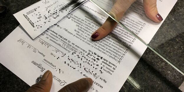 Eine weiße Hand, eine schwarze Hand, dazu Papiere Eine weiße Hand, eine schwarze Hand, dazu Papiere