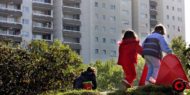 zwei kleine Kinder in Rückenansicht. Im Hintergrund Hochhausfassaden zwei kleine Kinder in Rückenansicht. Im Hintergrund Hochhausfassaden