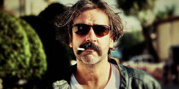 Deniz Yücel im Profil mit Sonnenbrille und einer Zigarette im Mund. Hintergrund ist unschaft. Deniz Yücel im Profil mit Sonnenbrille und einer Zigarette im Mund. Hintergrund ist unschaft.