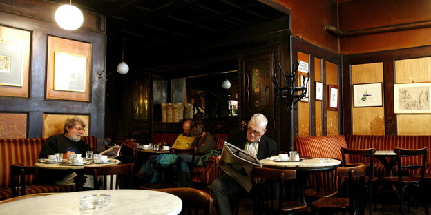In einem Kaffeehaus sitzen Männer und lesen In einem Kaffeehaus sitzen Männer und lesen