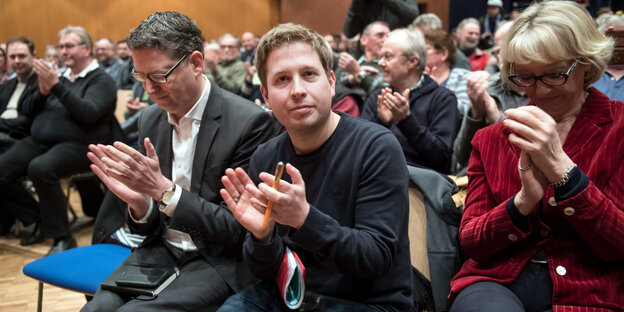 links zwei Männer, aplaudierend, rechts daneben eine Frau links zwei Männer, aplaudierend, rechts daneben eine Frau