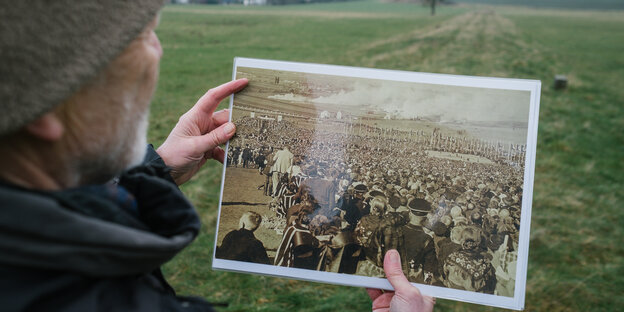 Ein Mann hält ein schwarz-weiß Foto auf dem ein Aufmarsch zu einem so genanntes Reichserntedankfest der Nazi zu sehen ist. Ein Mann hält ein schwarz-weiß Foto auf dem ein Aufmarsch zu einem so genanntes Reichserntedankfest der Nazi zu sehen ist.