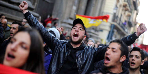 Demonstranten tragen ein rotes Banner und rufen laut Demonstranten tragen ein rotes Banner und rufen laut