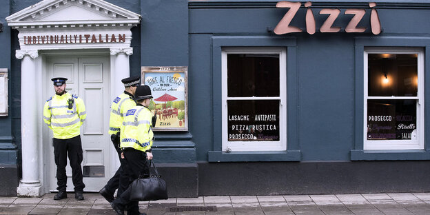 Die Front einer geschlossenen Pizzeria - davor Polizisten Die Front einer geschlossenen Pizzeria - davor Polizisten